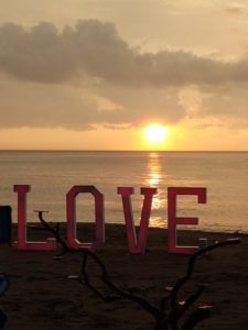 A sign saying LOVE and a sunset on the beach