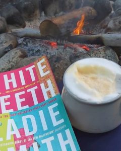 Book and coffee by a camp fire