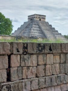 Temple at Chichen Itza and wall with skull carvings in the foreground